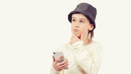 Pensive young boy with a serious face thinking about a question. Smart kid holding a mobile phone.