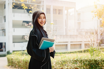 University saudi muslim niqab woman high education in university campus happy smiling with modern knowledge book. Arab saudi black chador lady.
