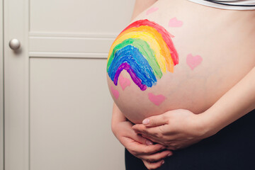 Belly painting, rainbow. Pregnant woman holding belly with painting. Waiting for baby concept. Belly painting and maternity photo