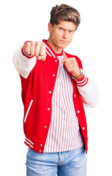 Young handsome man wearing baseball uniform punching fist to fight, aggressive and angry attack, threat and violence
