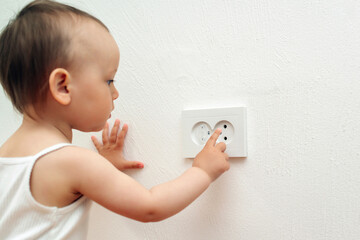 Child put finger in socket. Baby touching the power socket. Baby and child safety concept.