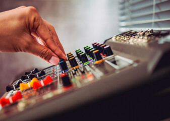 Close-up of sound engineer hands adjusting control sound mixer in recording, broadcasting...
