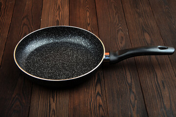 Metal frying pan: Ceramic coating with non-stick coating: Kitchen utensils; On a wooden background:...