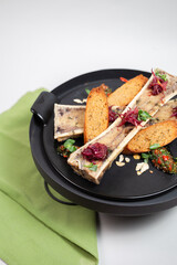 baked bone marrow with croutons, herbs and spices on a black plate