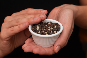 Bowl of Whole Peppercorns in a Female Hands. Gently holding a ramekin filled with assorted whole...
