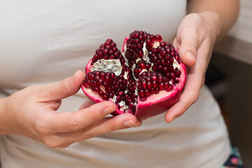 Female Hands Holding Open Pomegranate. Cradling a freshly opened pomegranate revealing juicy seeds.