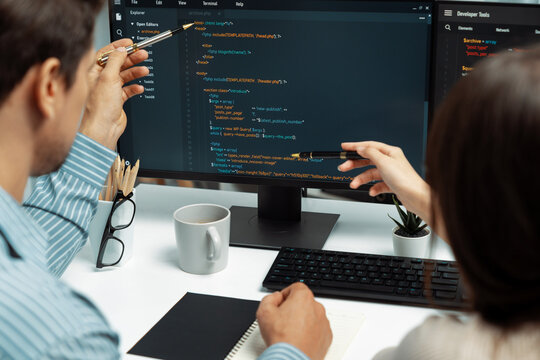 Team skilled developers program coding discussing creative website planning software project on two screen monitor's full stack data analyzing design at office with back side view concept. Postulate.