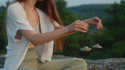 Young woman meditating with Tibetan meditation Tingsha hand bells at sunset.