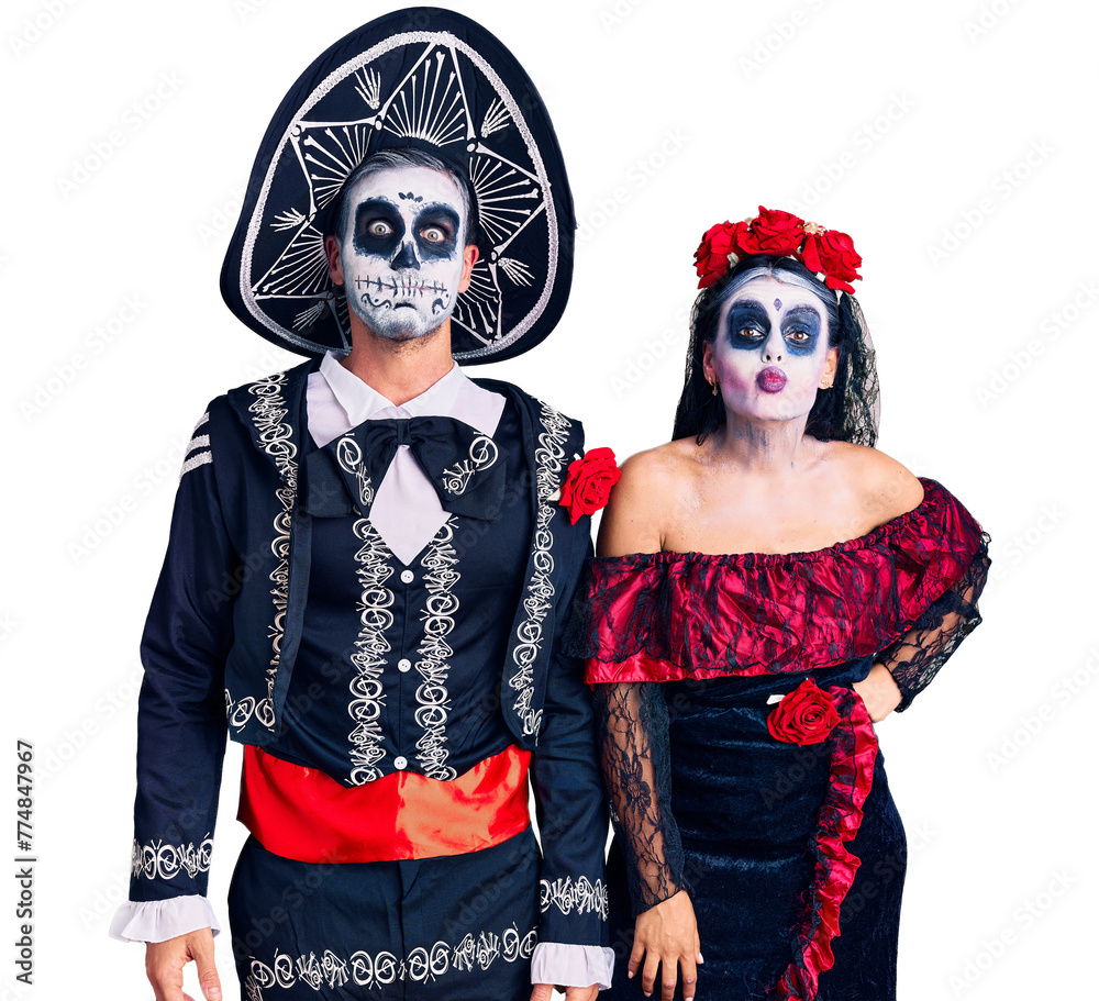 Wall mural young couple wearing mexican day of the dead costume over background puffing cheeks with funny face.