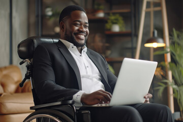 Smiling african american businessman with disability in wheelchair chair using laptop, working despite disability
