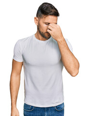 Fototapeta premium Handsome man with beard wearing casual white t shirt tired rubbing nose and eyes feeling fatigue and headache. stress and frustration concept.