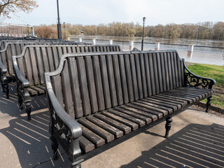 Wooden bench on the embankment of the river in the city