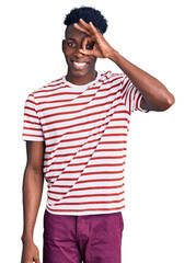 Young african american man wearing casual clothes doing ok gesture with hand smiling, eye looking through fingers with happy face.