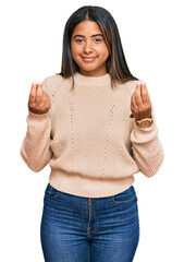 Young latin girl wearing wool winter sweater doing money gesture with hands, asking for salary...