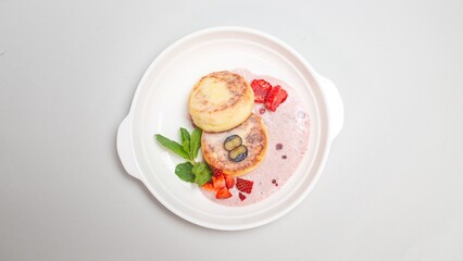 Top view of delicious cottage cheese pancakes with berries on a plate on a white background