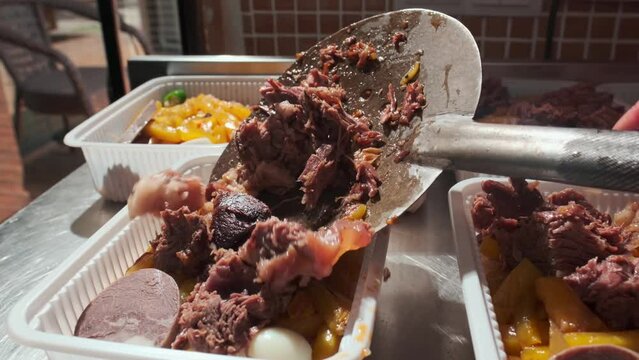 The chef lays out the cooked meat in plastic containers with Uzbek pilaf