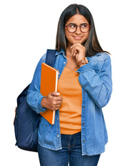 Young latin girl wearing student backpack and holding books thinking worried about a question, concerned and nervous with hand on chin
