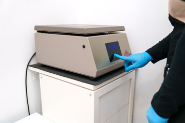 Gloved hand on a centrifuge's touch panel.