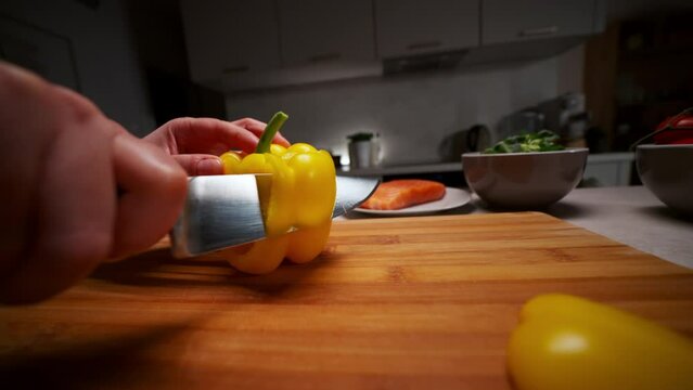 Close up image of cutting board and woman cutting pepper vegetables in the kitchen, preparing food meal at home