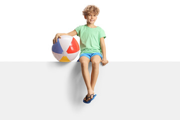 Fototapeta na wymiar Boy with a beach ball sitting on a blank panel