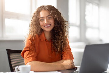 Happy young woman posing at her workstation