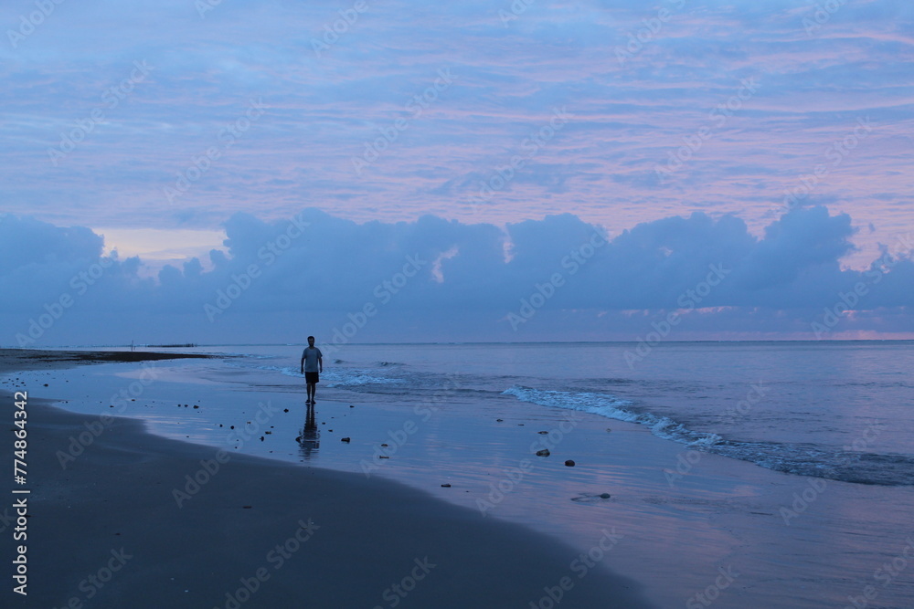 Wall mural homem caminhando na beira da praia em amanhecer em tatuamunha, alagoas