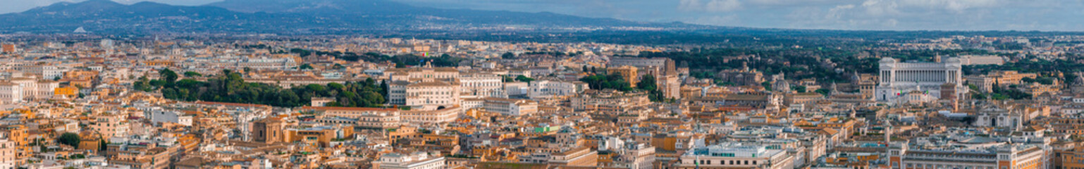 Naklejka premium An aerial panorama of Rome shows terracotta rooftops and green canopies, blending ancient and modern architecture.