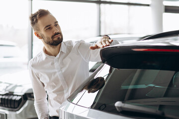 Business man in car showroom choosing a car