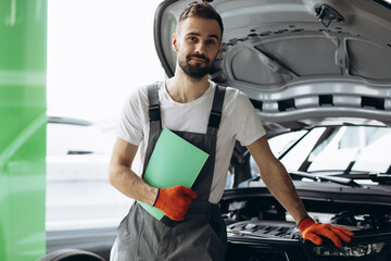 Car mechanic holding documents and checking car