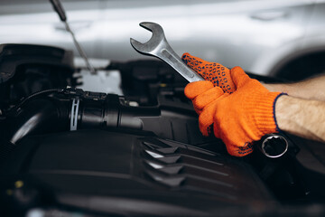Car mechanic holding wrench for car repair