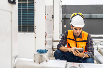 Male technical foreman in safety uniform inspects maintenance work holding a tablet to look at...