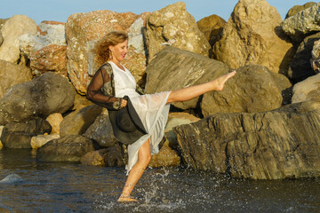 Woman Kicking Water on Rocky Beach