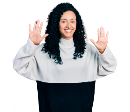 Young hispanic woman with curly hair wearing casual sweater showing and pointing up with fingers number ten while smiling confident and happy.