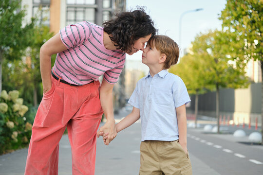 Adorable mother and son smiling happy having fun at city background. Motherhood concept, hugging. Boy 8 years old with mother in bright clothes enjoying summer day. High quality photo