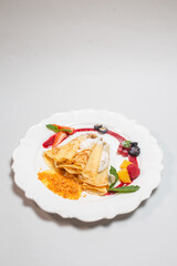 Delicious pancakes with berry and cream filling and jam on a white background.