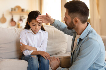 Fototapeta premium Father checking his daughter's forehead for fever