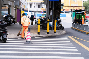 Man sweeps the streets with a broom, clean city streets Clean the city from garbage. Municipal workers in orange uniforms sweep the streets