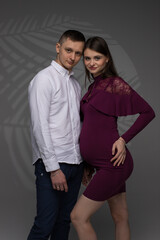 portrait of a couple, pregnant couple on a grey background close up, fashion pregnant model, pregnant woman stands on a grey background, studio shoot
