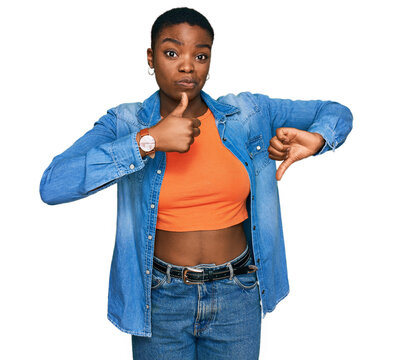 Young african american woman wearing casual clothes doing thumbs up and down, disagreement and agreement expression. crazy conflict
