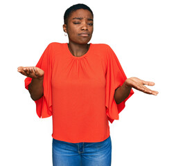 Young african american woman wearing casual clothes clueless and confused expression with arms and...