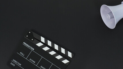 Black clapperboard or movie clapper board and megaphone on black background.