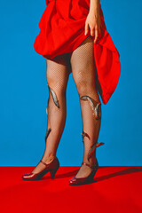 Cropped image of female legs in fishnet stocking, red heels and fishes stacking into stockings against blue background. Concept of pop art photography, creativity, food, surrealism, fashion