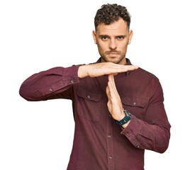Young hispanic man wearing casual clothes doing time out gesture with hands, frustrated and serious...