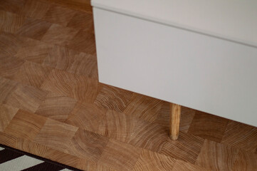 A white wooden dresser on legs on a wooden floor background