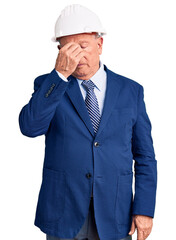 Senior handsome grey-haired man wearing suit and architect hardhat tired rubbing nose and eyes feeling fatigue and headache. stress and frustration concept.