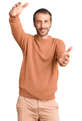 Fototapeta premium Young handsome man wearing casual clothes looking at the camera smiling with open arms for hug. cheerful expression embracing happiness.