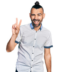 Hispanic man with ponytail wearing casual white shirt smiling with happy face winking at the camera...