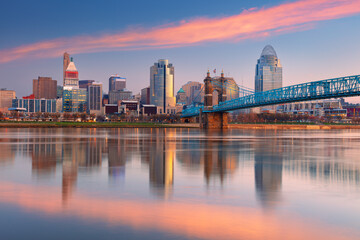Cincinnati, Ohio, USA. Cityscape image of Cincinnati, Ohio, USA downtown skyline with the John A. Roebling Suspension Bridge and reflection of the city in the Ohio River at spring sunrise. - obrazy, fototapety, plakaty