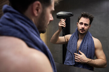 Caucasian man drying hair in the bathroom - 774908915