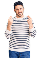 Young hispanic man wearing casual clothes doing money gesture with hands, asking for salary...